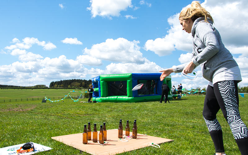 A girl throwing a hoop around some bottles in Geordie Games