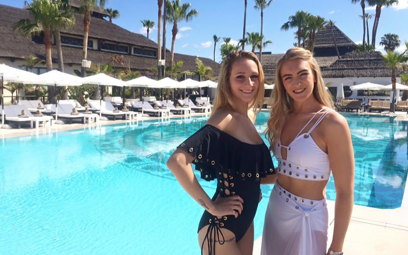 Two women in swimwear in front of a swimming pool