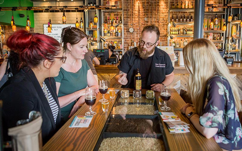 A group of people sat at a table in a bar, with glasses of wine on the table