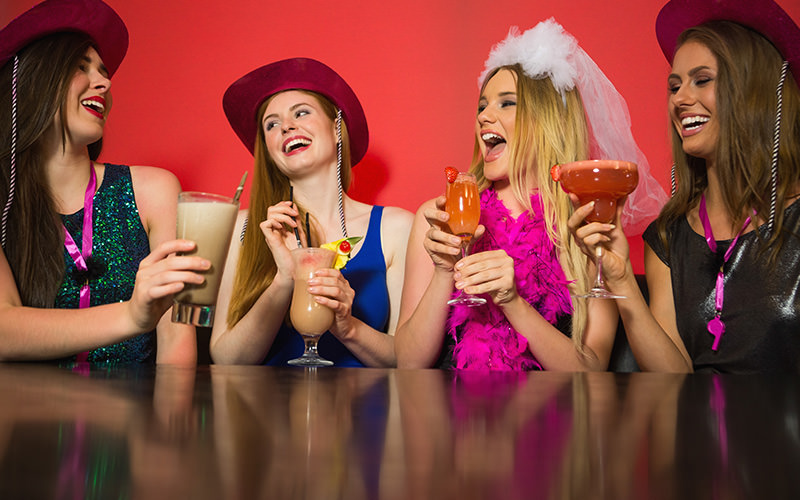 Four women sat around a table, drinking cocktails