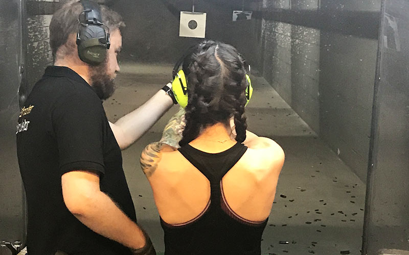The back of a woman's head wearing protective ear guards, aiming at a target