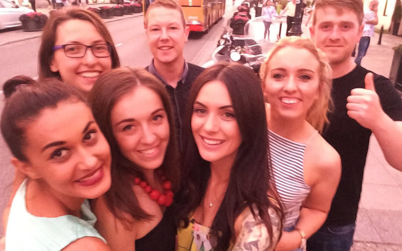A group of men and women outside, smiling at the camera