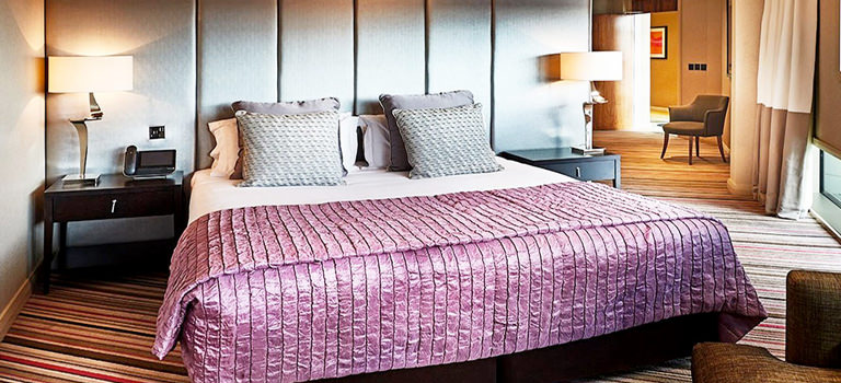 A double room in a hotel with a purple throw over