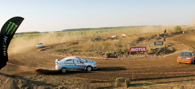 Some rally cars driving around a dusty circuit