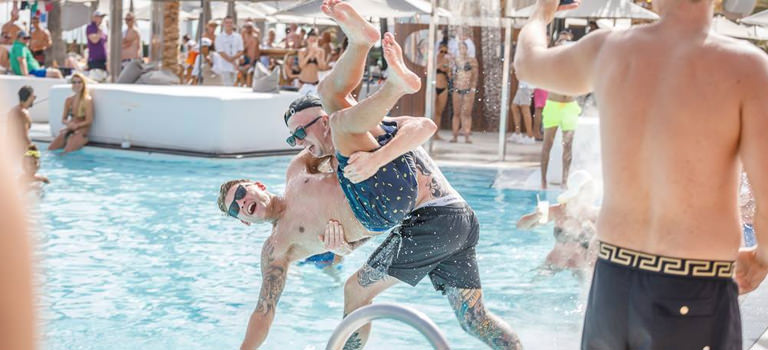A man pushing another man into a pool