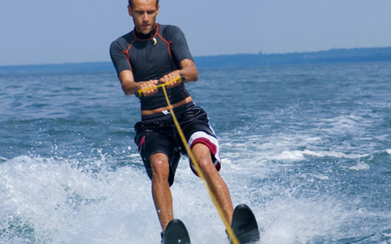 A man wakeboarding whilst holding the rope which is attached to a boat