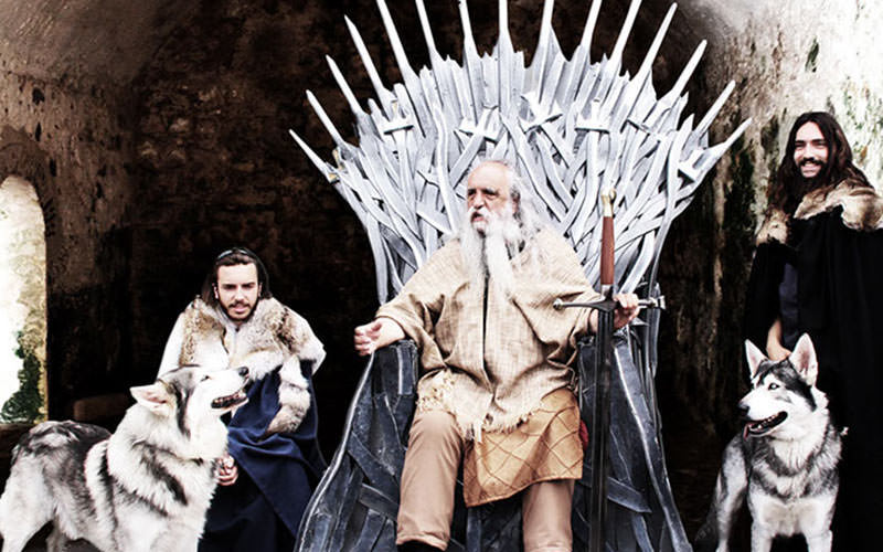 Three men from Game of Thrones, the middle on a throne and two with dogs