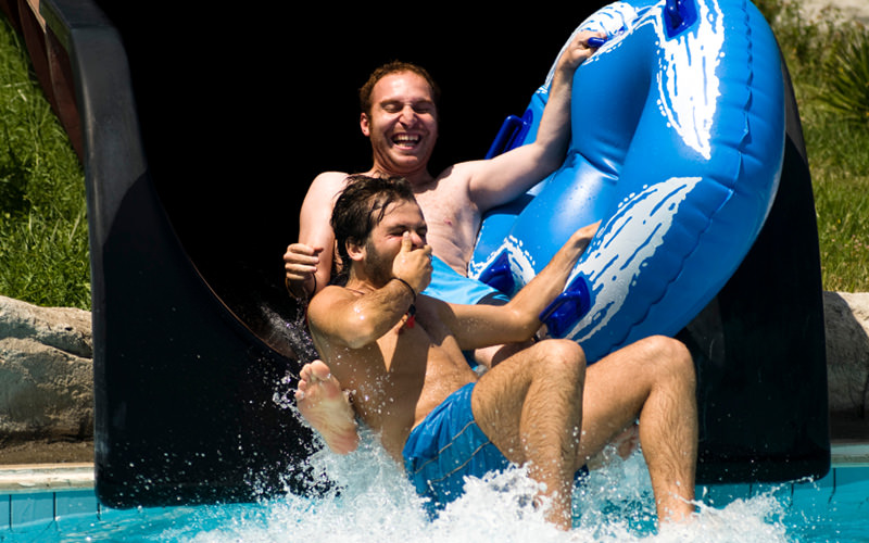 Two men coming down from a water flume