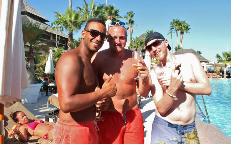 Three men with drinks by the poolside