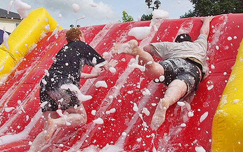 Two men attempting to climb a slippery slope on an obstace course