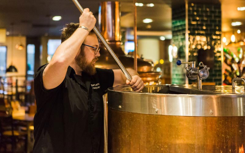 A man stirring a pot in a brewery