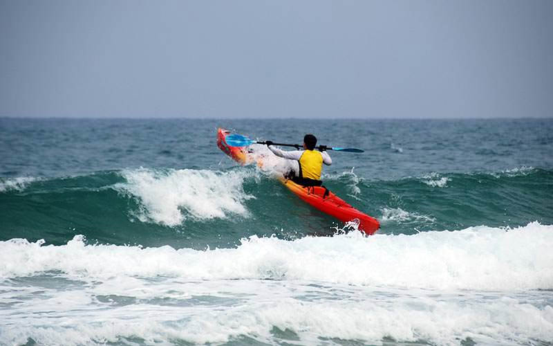 A man canoeing out onto the sea