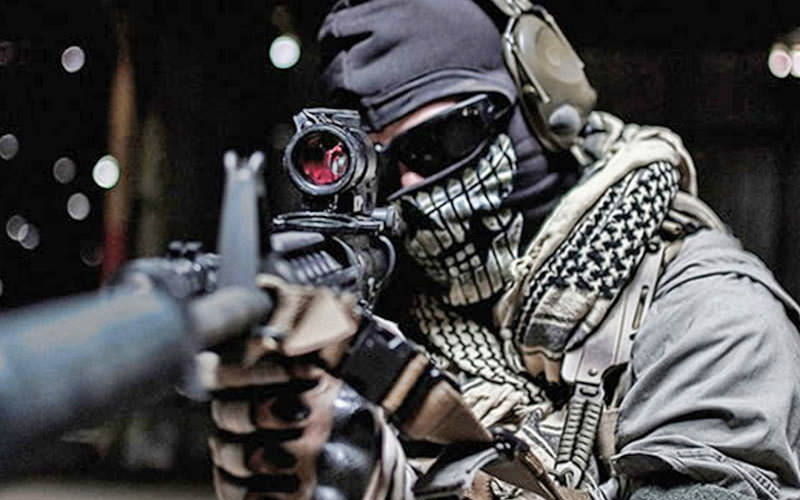 A man wearing combat gear, holding a gun