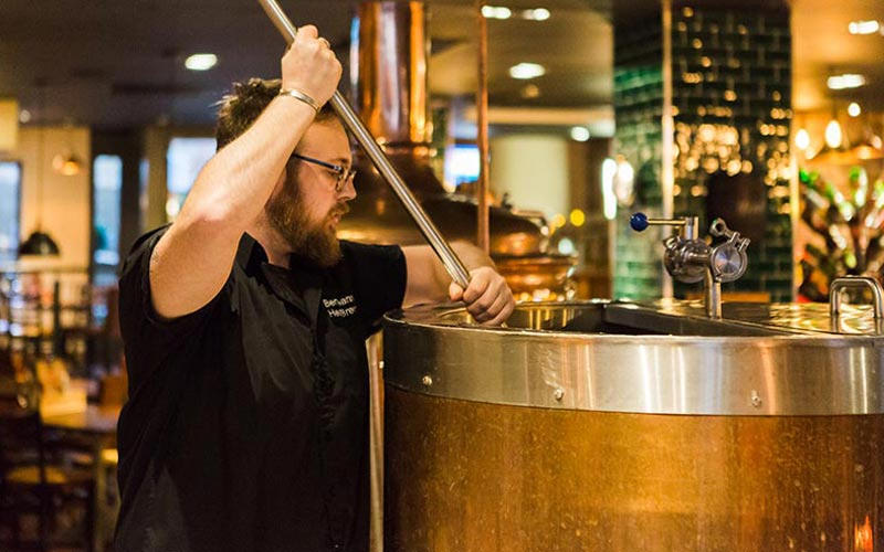 A man stirring a keg in a brewery