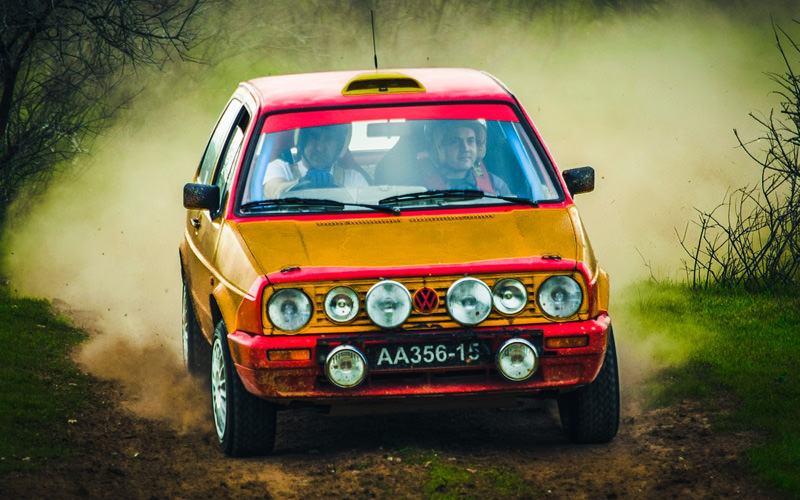 Two men driving in a small orange car