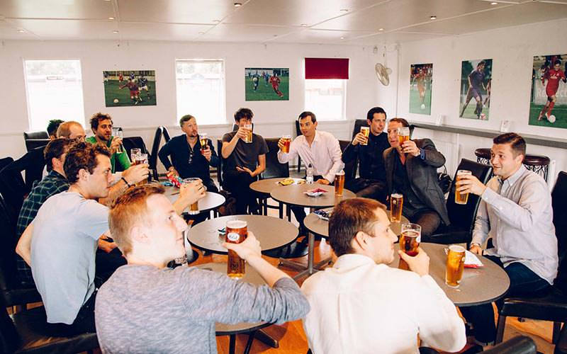 Some lads holding beers up as if they're toasting