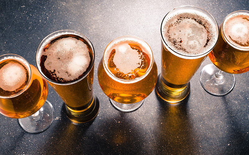 Five beers lined up on a black table top