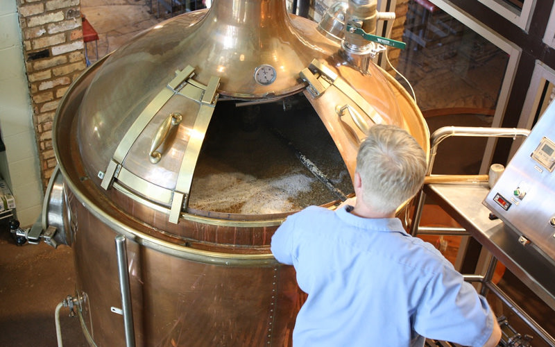 A brewer tending to a keg of beer, during the fermentation process