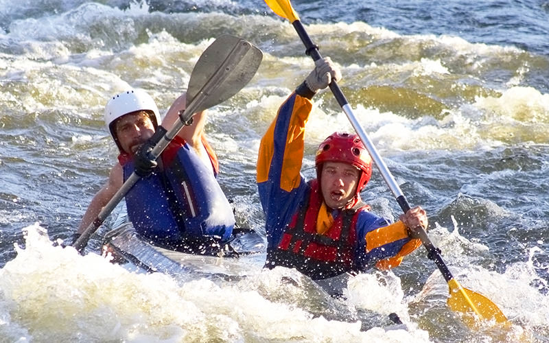 Two men paddling against the white water rapids