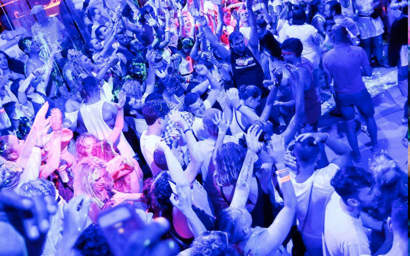 A large group of people clubbing under blue light