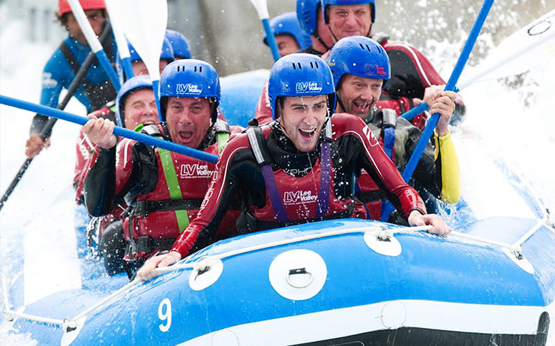 Lots of men in a raft, heading down the white water rapids