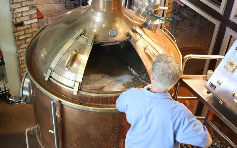 A man demonstrating how to use machinery in the beer factory