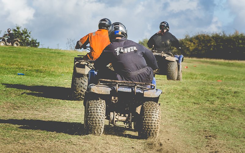 A group of men on quad bikes in a muddy field