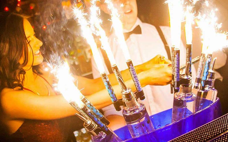 A woman in a nightclub serving drinks with sparklers