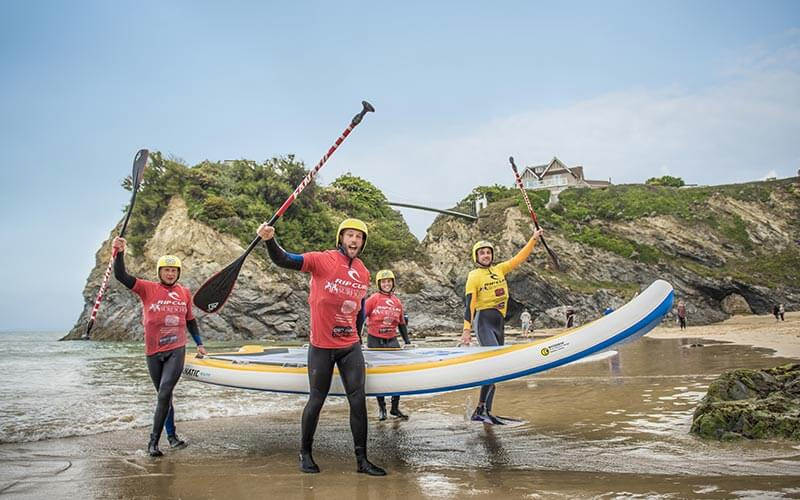 Some men carrying a surfboard along the beach