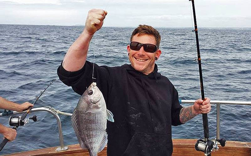 A man holding up a fish he has caught, proudly