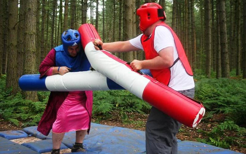 Two men pole jousting in the woods