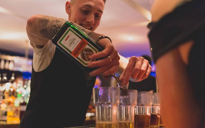 A barman pouring Jagermeister into glasses of Red Bull