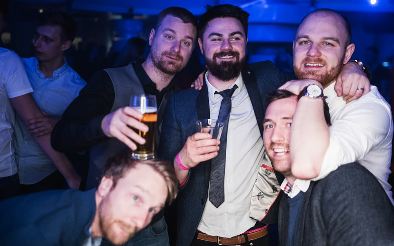 A group of men in a club, holding drinks