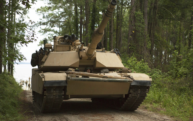 A tank going along a track, with trees surrounding it
