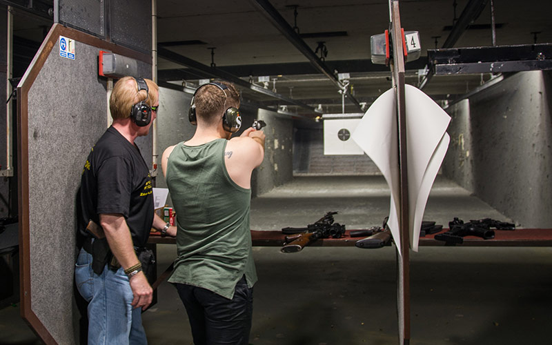 A man being shown how to fire a gun in a shooting activity