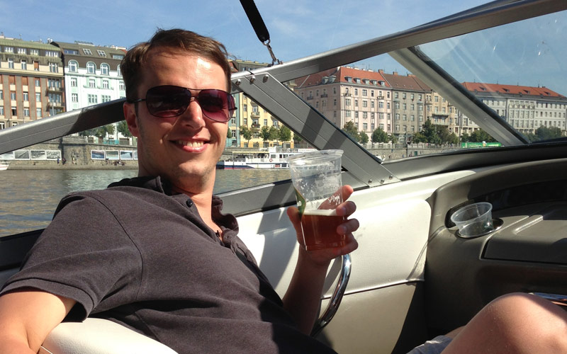 A man holding a beer whilst sitting in a speed boat in Prague