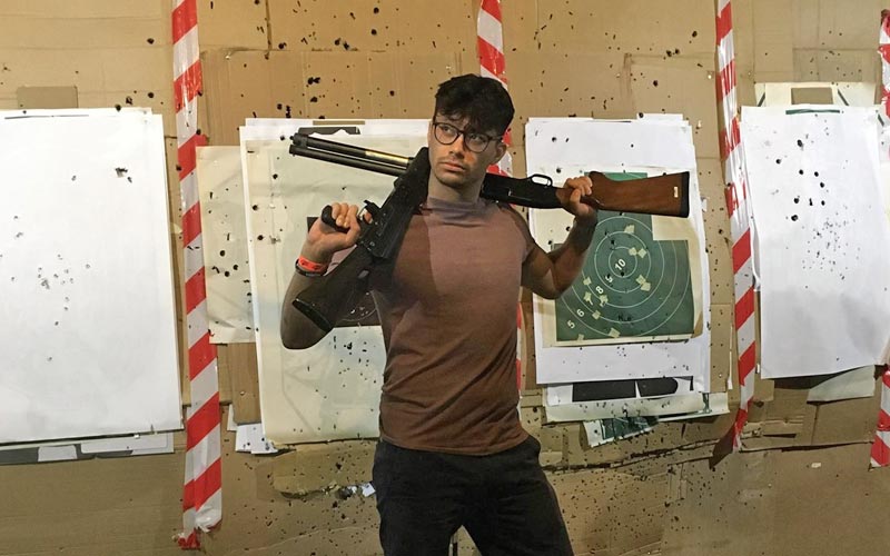  A man posing with two guns in front of a target