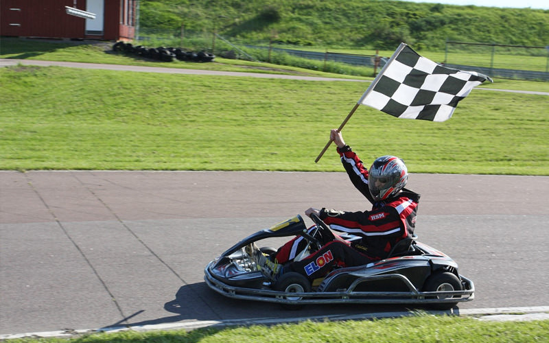 Someone driving a go kart waving a checkered flag in the air