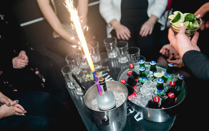 A table with two ice buckets and various drinks in them, along with a sparkler