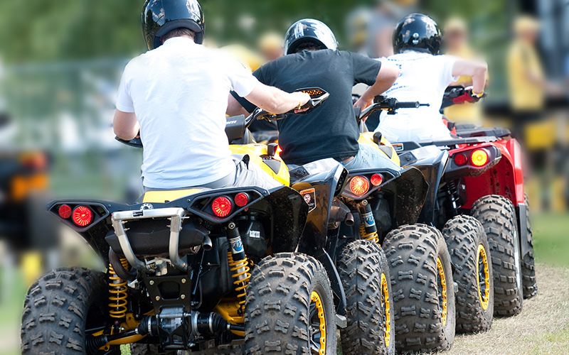 Three people riding on quad bikes