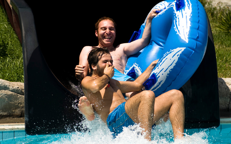 Two men coming out of a water slide