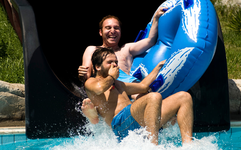 Two men coming out of a water slide