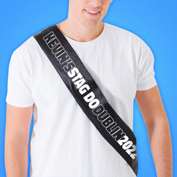 A man in a white T-shirt wearing a custom sash.