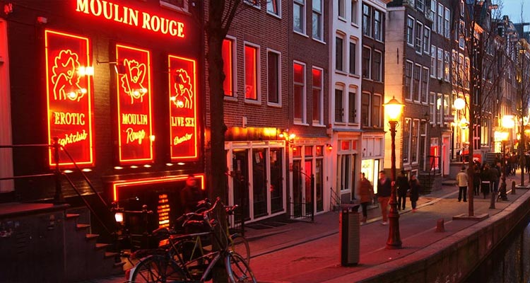 A canal illuminated at night in De Wallen
