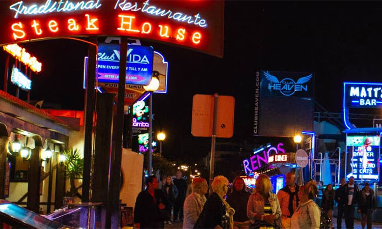The Albufeira strip that is packed with bars with neon signs including a steak house, Heaven and Matt