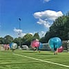  People playing bubble football under a blue sky