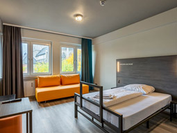 A single room with a sofa and desk area at A&O Koln Hauptbahnhof in Cologne