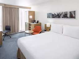 A double bed in a room with a desk area, large windows and lots of storage at DoubleTree By Hilton Manchester Piccadilly