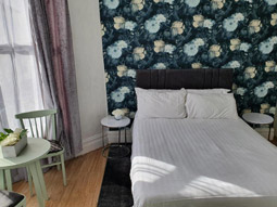 A double bed with a table and set of chairs in a room at Balkan Hotel in Blackpool