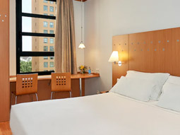 A king room with a desk and chairs that face a view of the city at NH Valencia Las Ciencias